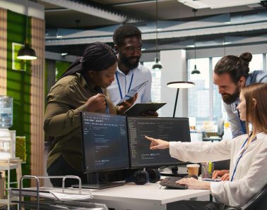 Welcoming team assisting intern developing artificial intelligence models for business analytics. Friendly coworkers helping junior dev running simulations for AI driven forecasting, camera A