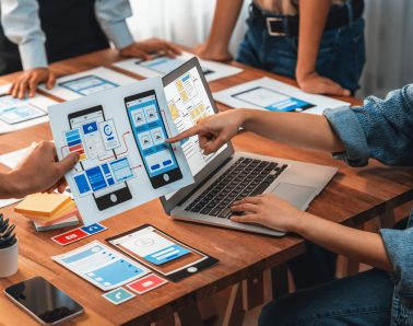 Panorama shot of front-end developer team brainstorming UI and UX designs for mobile app on paper wireframe interface. User interface development team planning for user-friendly UI design. Scrutinize